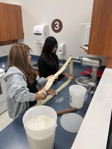 Students make pasta with a pasta maker 