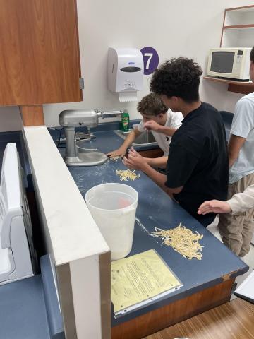 Students make pasta with a pasta maker 